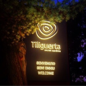 Een bord met de naam 'Tiliguerta' en de woorden 'geheime Sardinië' en 'welkom' in verschillende talen.