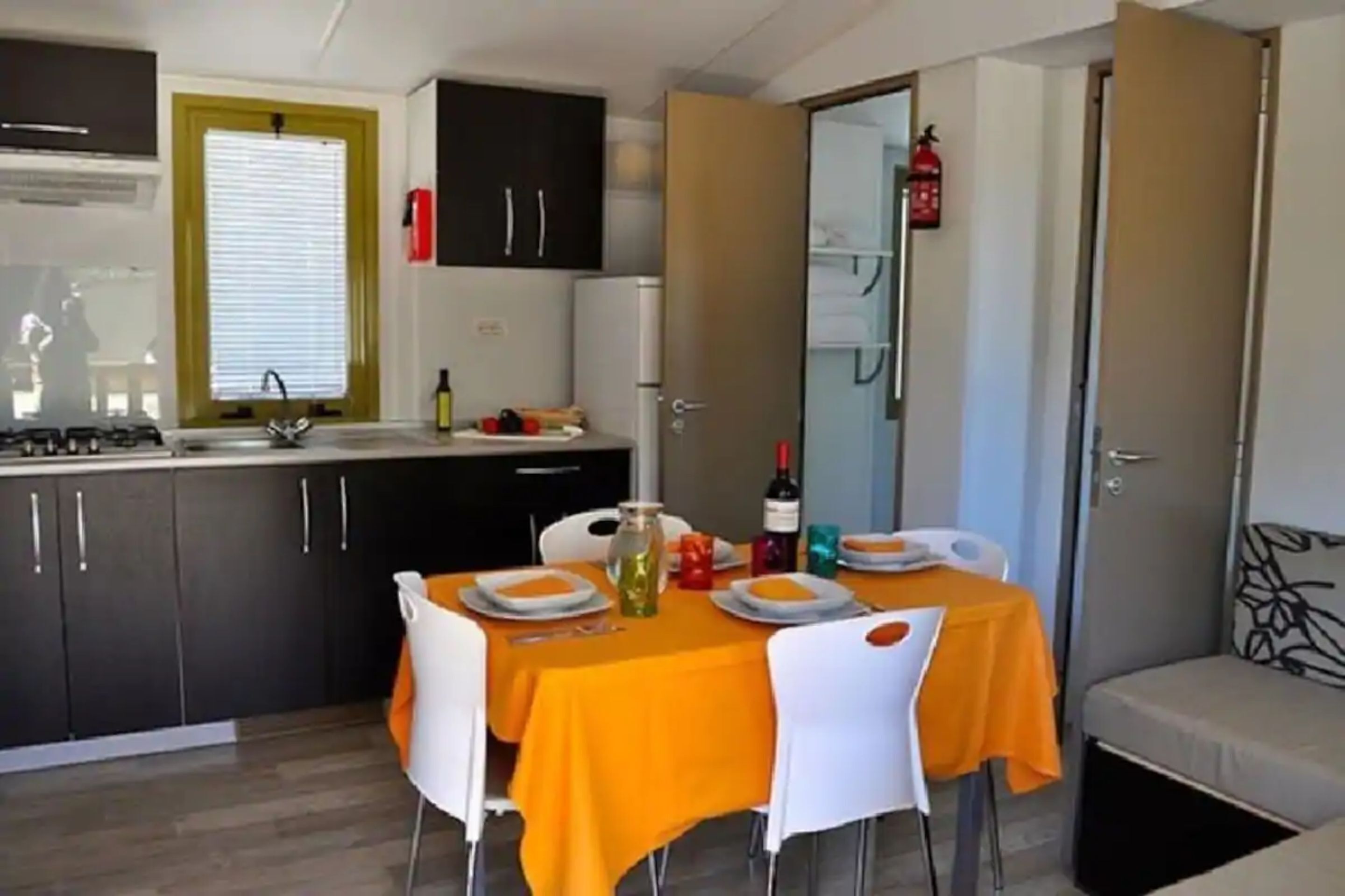 Una cucina funzionale con mobili scuri, un lavello e un'area pranzo con tavolo imbandito per due persone.