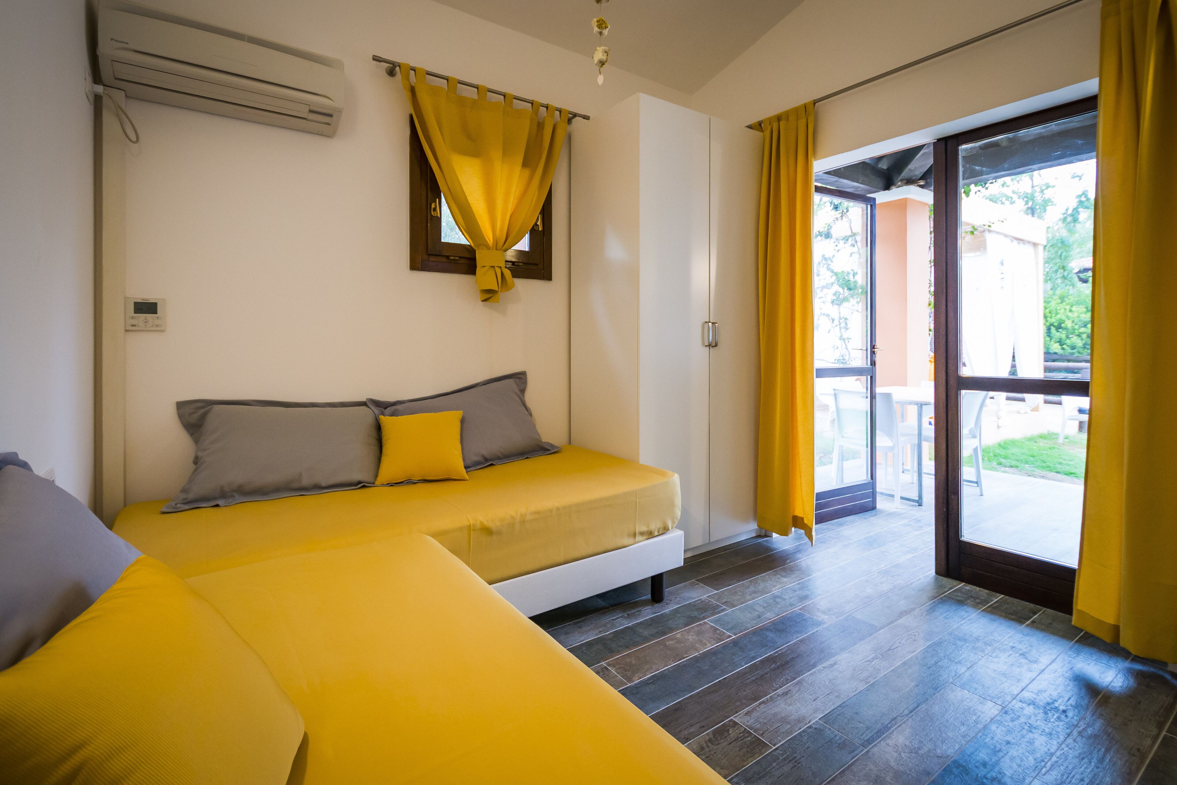 Una habitación con una cama, una ventana con cortinas amarillas y vistas al exterior.