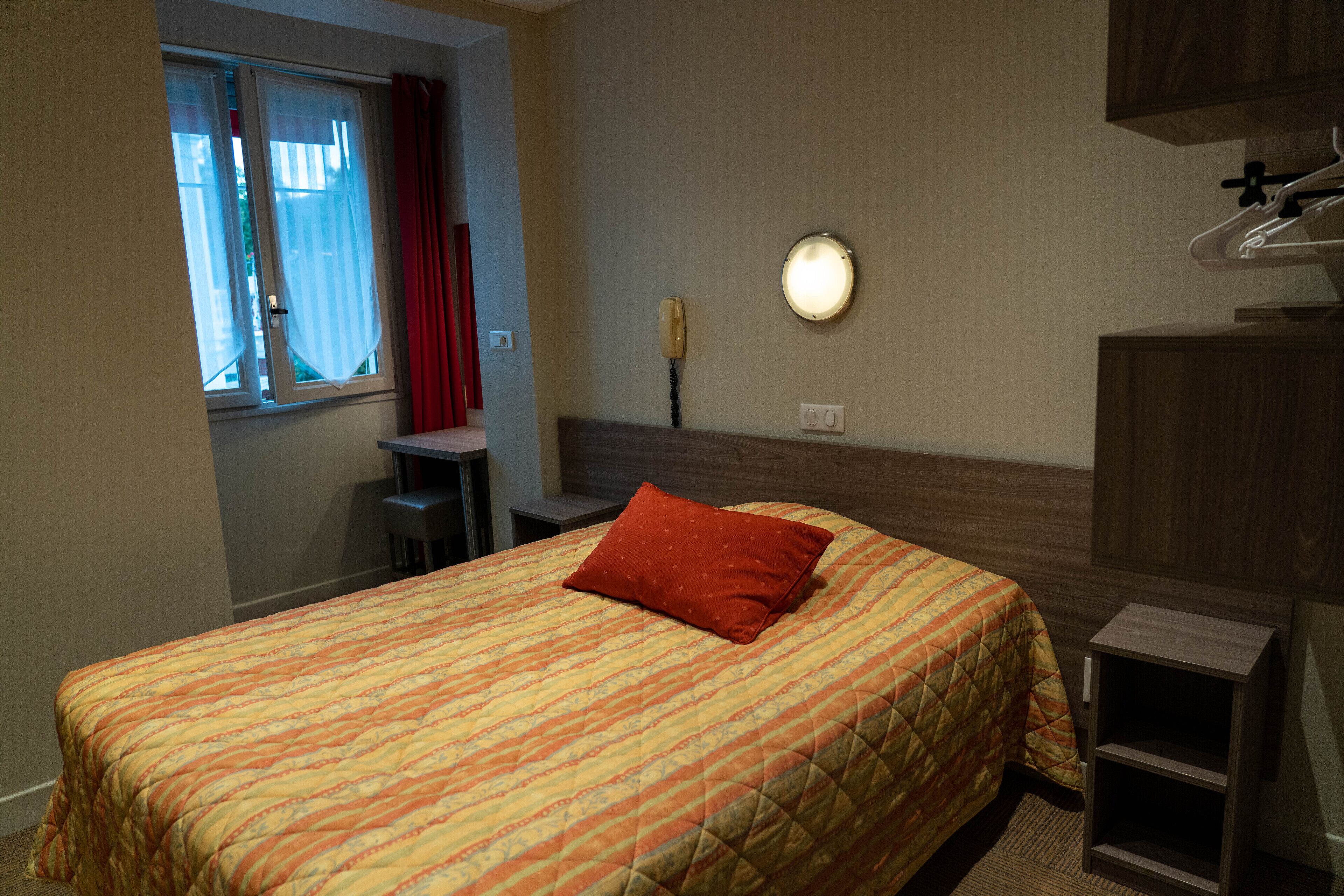 Een hotelkamer met een bed, een bureau, een stoel, een telefoon en een nachtkastje.