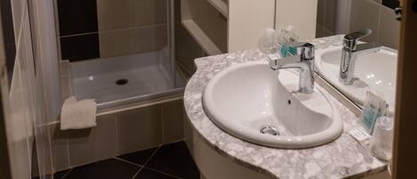 Un baño con ducha, lavabo y espejo.