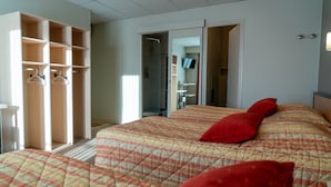 A bedroom with a bed, a wardrobe, and a bathroom visible through an open door.