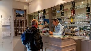 A hotel reception area with a glass counter, a menu board, and a view of the mountains.