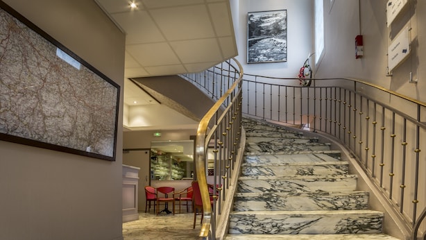 A marble staircase with a metal railing and a wall-mounted fire extinguisher.