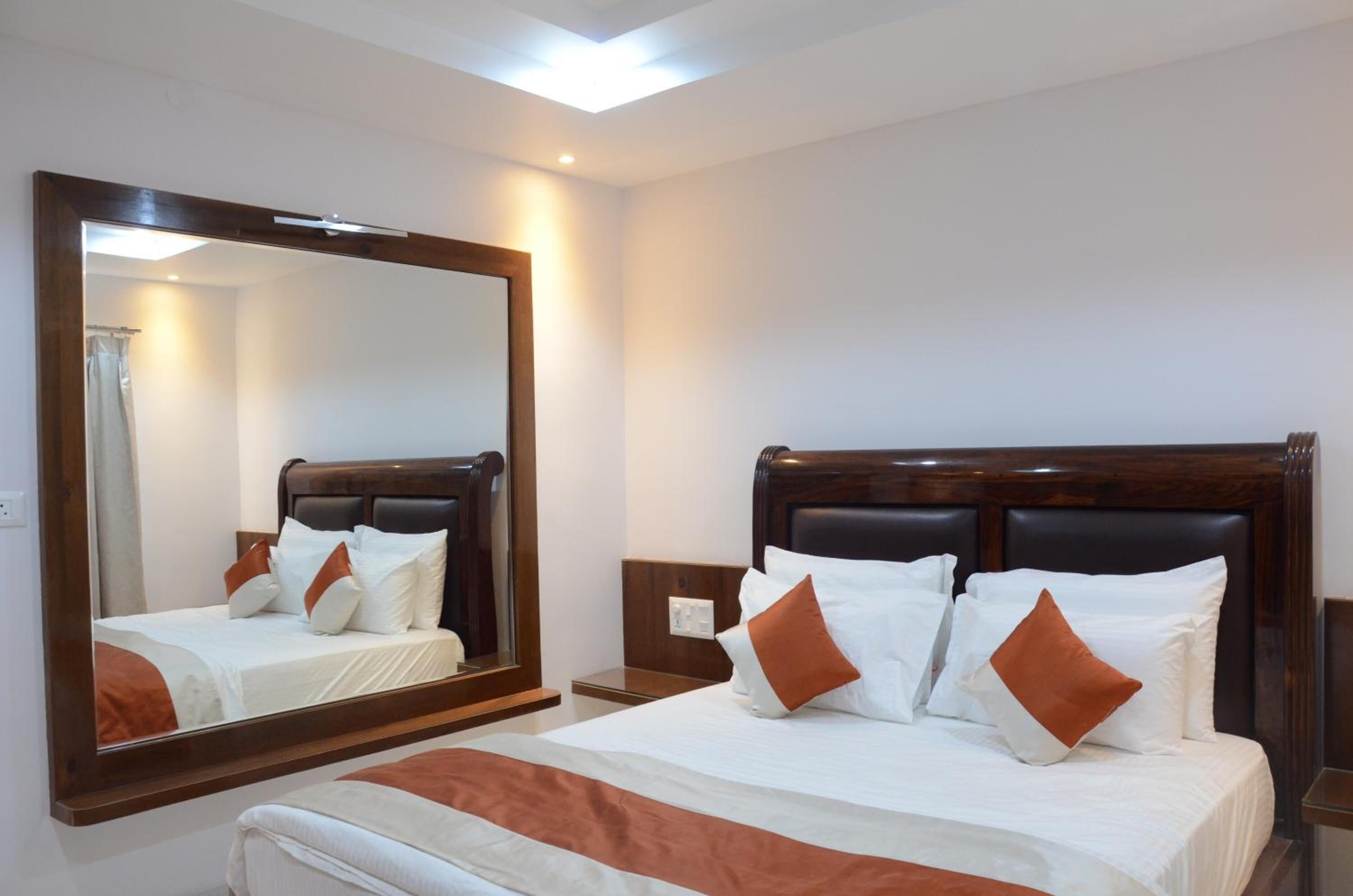 Een hotelkamer met een groot bed, een houten hoofdeinde, een nachtkastje en een grote spiegel.