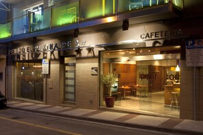 Un edificio con un letrero que dice "CAFETERIA" y una planta en maceta afuera.