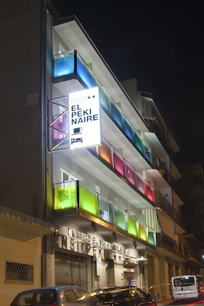 A multi-story building with a brightly lit sign reading "PENIBIO EL PEKI NAIRE" and a visible storefront below. - B&B El Pekinaire (Calella)