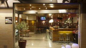 Un espace bar moderne avec des tabourets, une grande plante en pot et un panneau indiquant la présence d’une connexion Wi-Fi.