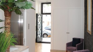 A modern interior with a staircase, a plant, two purple chairs, and a view of a car through an open door. - Lisbonne Appartements (Lisbon)