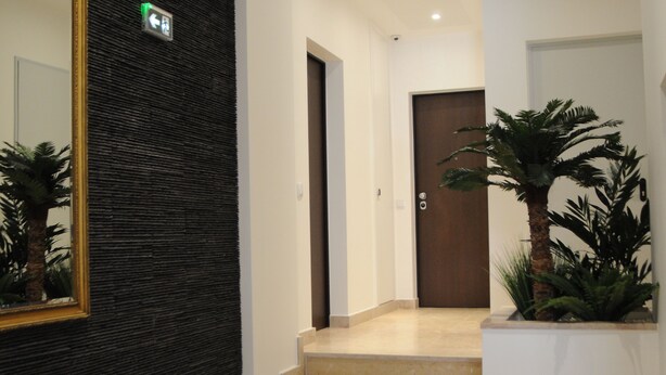 A modern hotel lobby with a staircase, a chair, a large mirror, and a potted plant. - Lisbonne Appartements (Lisbon)