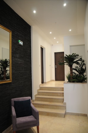 A modern hotel lobby with a staircase, a chair, a large mirror, and a potted plant. - Lisbonne Appartements (Lisbon)