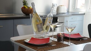 A dining table with a bottle of wine, two glasses, a bowl of fruit, and a toaster. - Lisbonne Appartements (Lisbon)