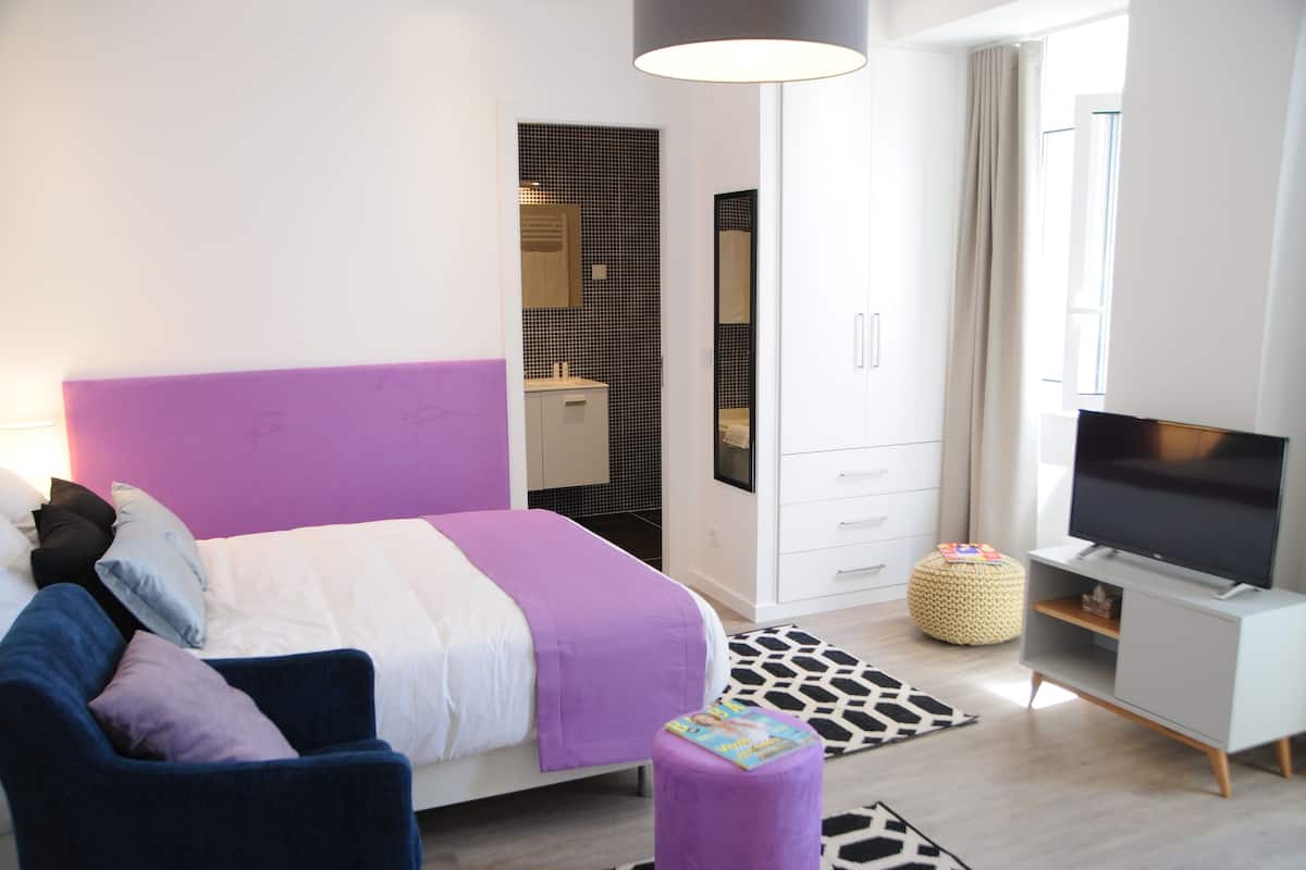 Une chambre moderne avec un lit, une télévision, un canapé et une armoire.