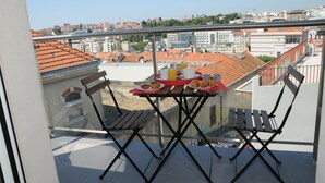 A balcony with a table set for breakfast, overlooking a cityscape with red-tiled roofs. - Lisbonne Appartements (Lisbon)