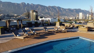Una piscina al aire libre, sillones reclinables de piscina