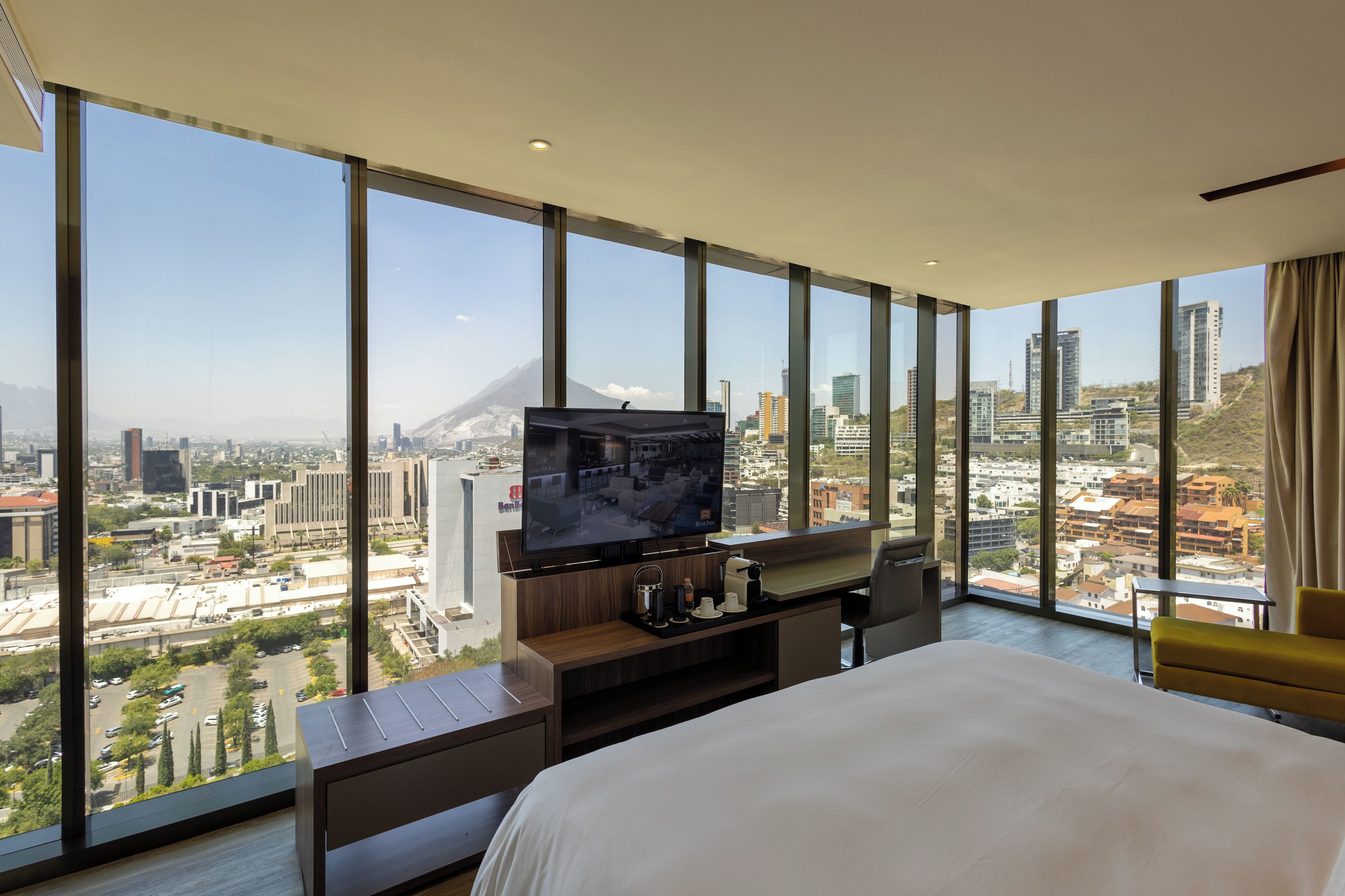 Habitación de hotel con una cama grande, televisión y vistas a la ciudad.