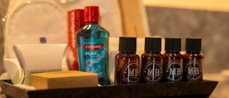 A tray with a bar of soap, a bottle of Colgate toothpaste, and four bottles of MR London essential oils.