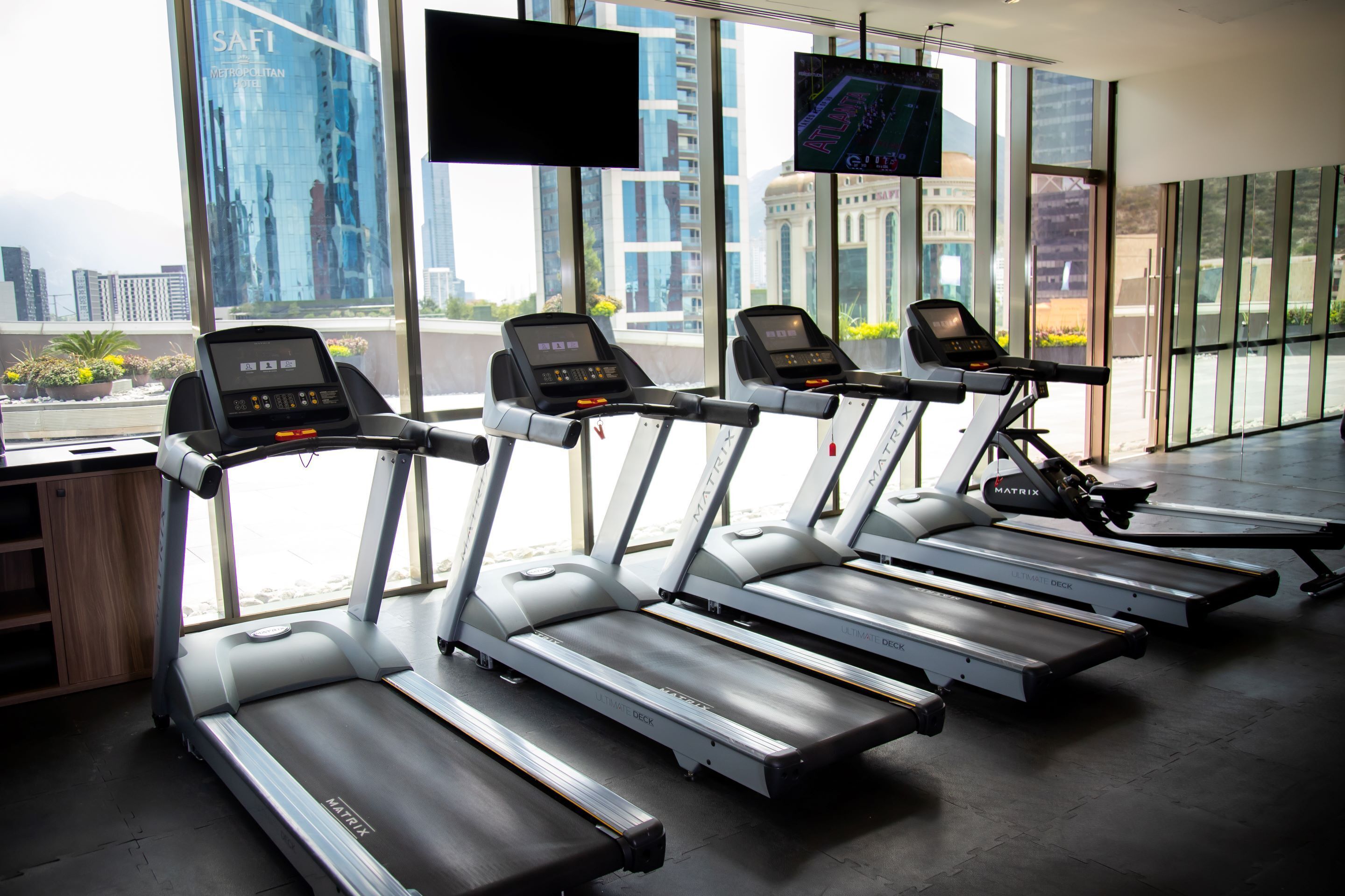 A gym with treadmills, large windows, and a city view.