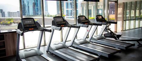 A gym with treadmills, large windows, and a city view.