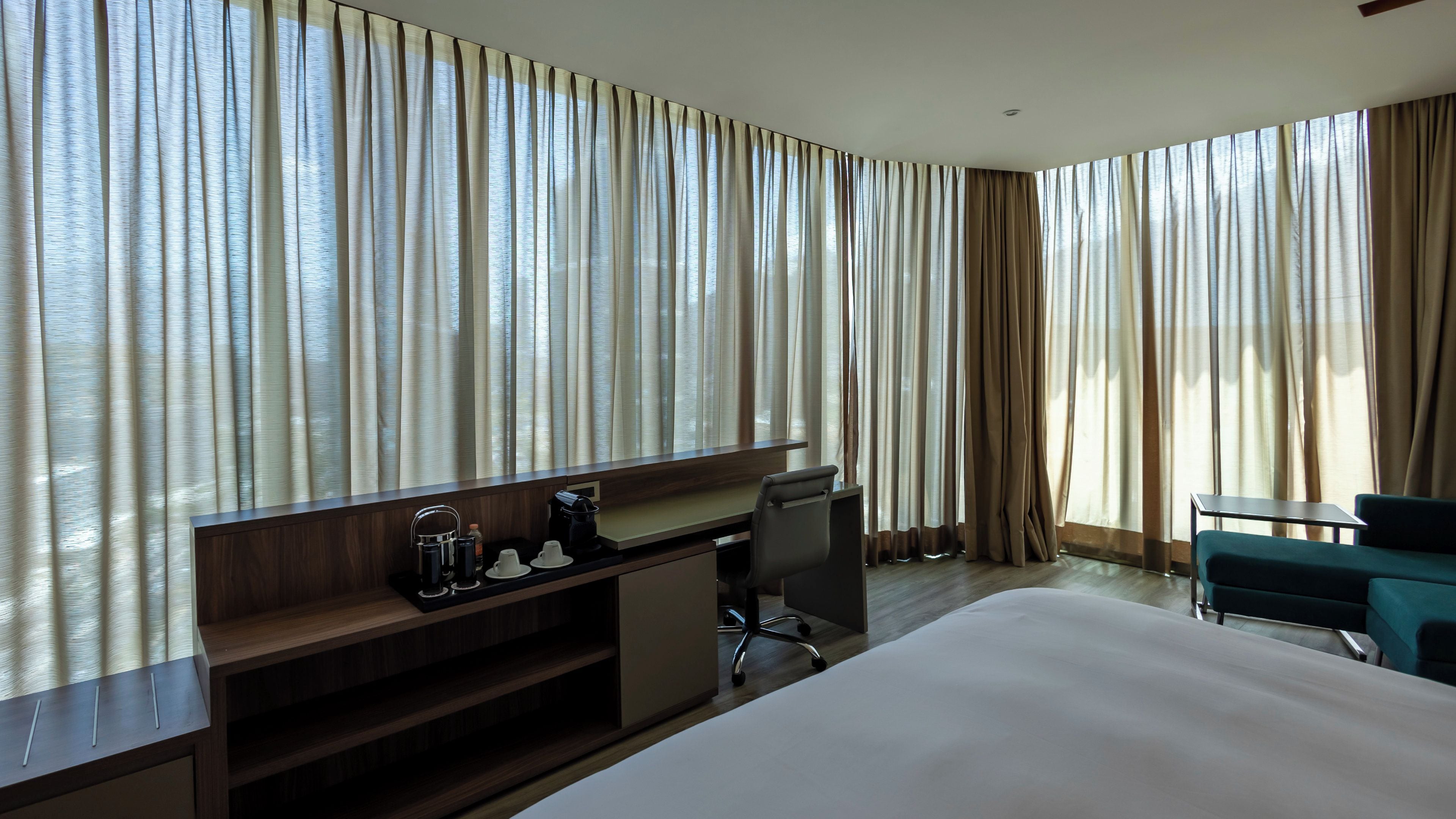 Une chambre d’hôtel avec un lit, un bureau, une chaise et des rideaux.