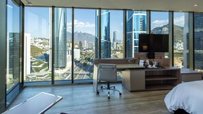 A hotel room with a large window, a desk, a chair, a bed, and a television. - Camino Real Fashion Drive Monterrey (San Pedro Garza García)