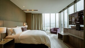 Quarto de hotel moderno com uma cama grande, uma mesa, uma cadeira e uma televisão.