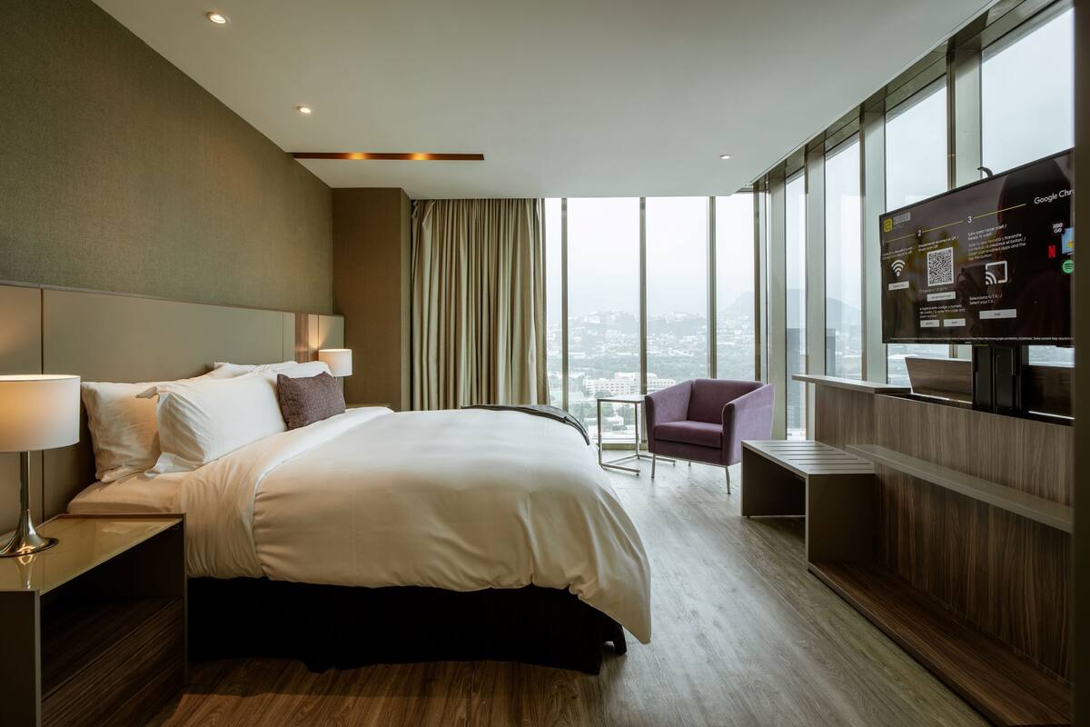 Une chambre d’hôtel moderne équipée d’un grand lit, d’un bureau, d’une chaise et d’un téléviseur.