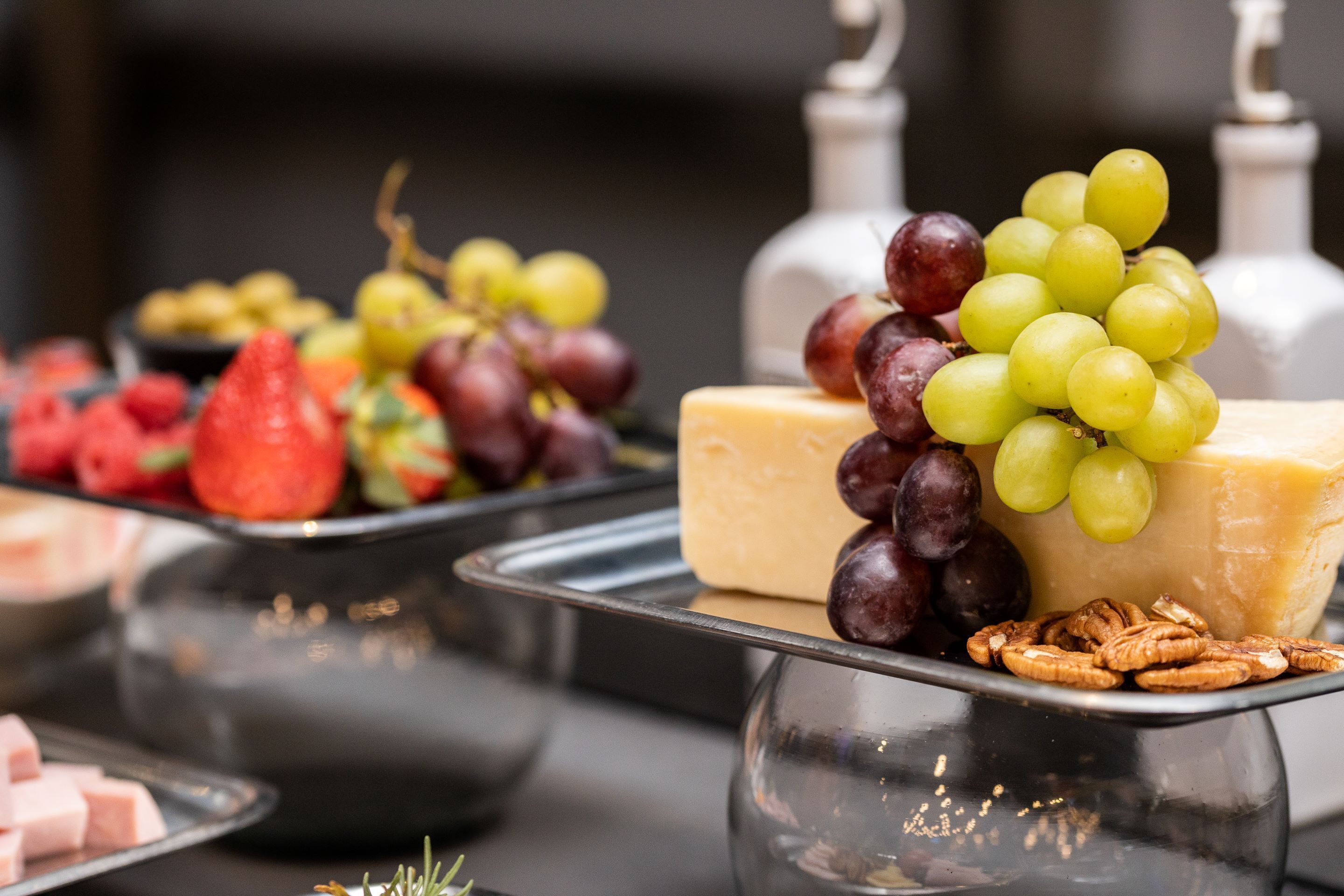 Buffet com diversos queijos, uvas e frutas.