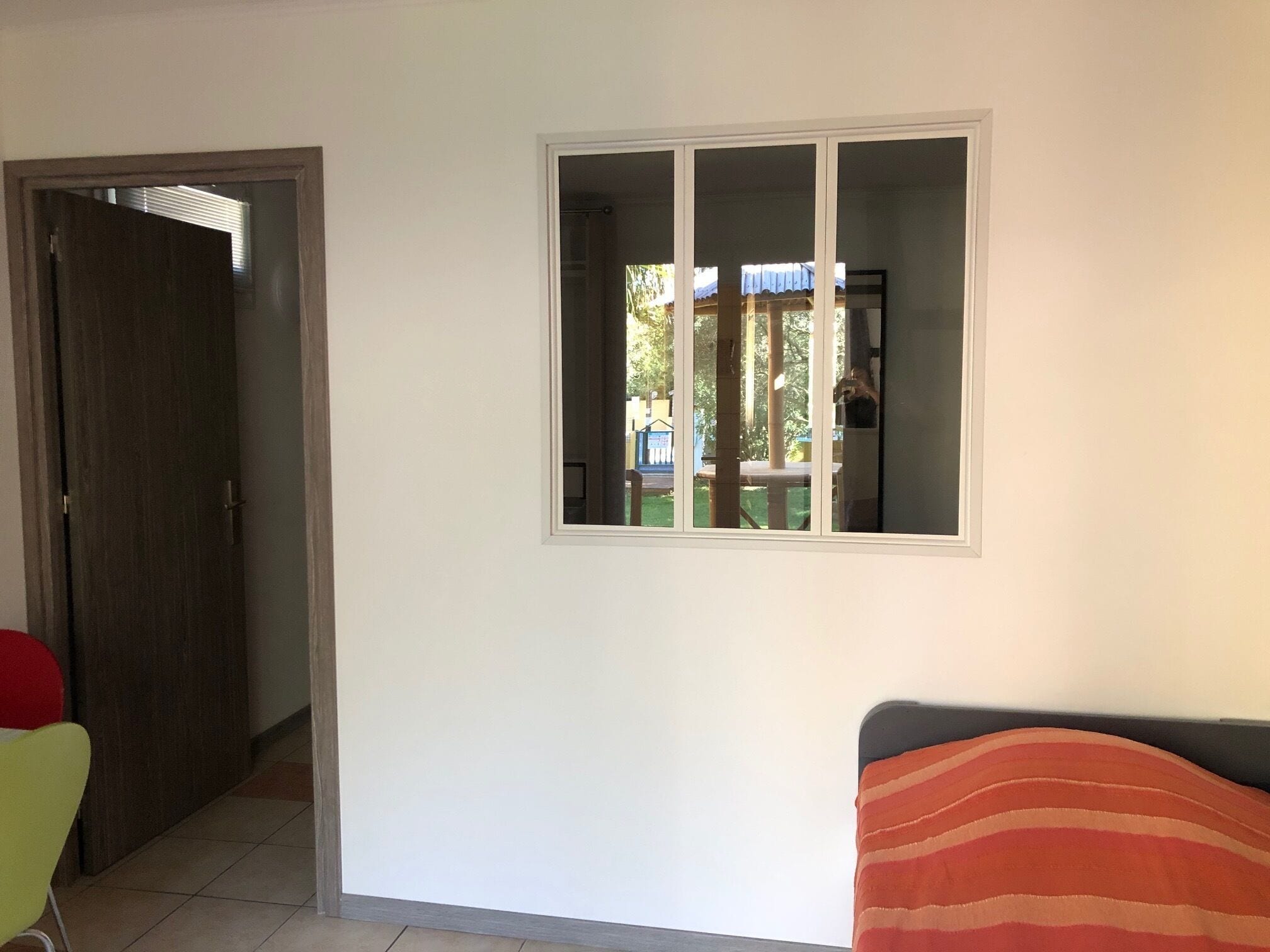 A room with a bed, a window, a door, and a chair.