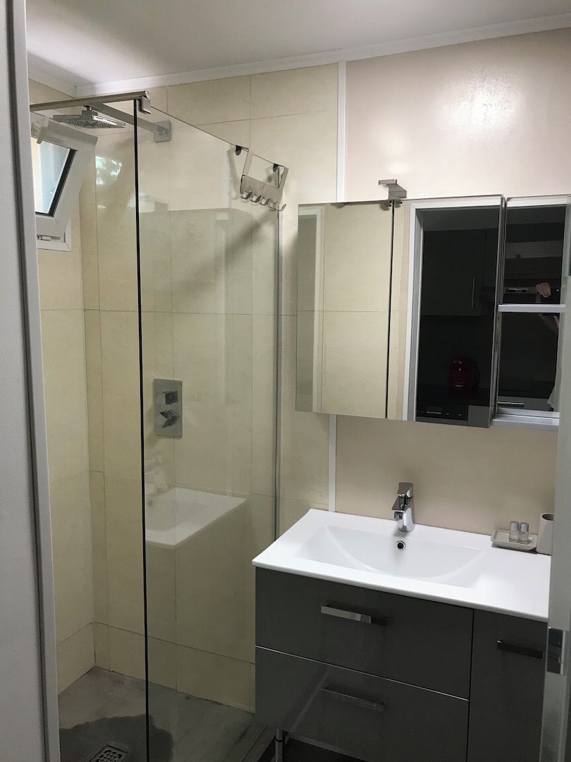 A modern bathroom with a glass-enclosed shower, a white sink, and a mirror above the vanity.
