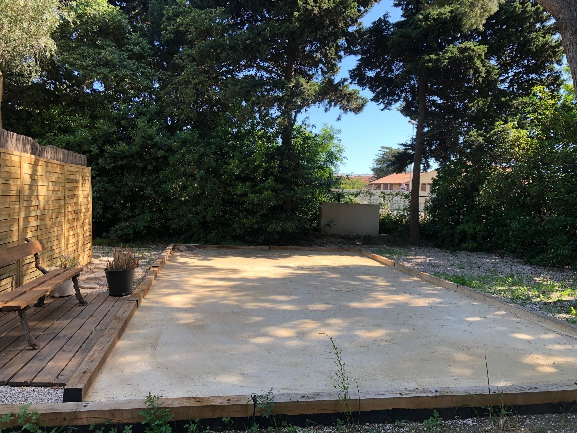 Une terrasse en béton avec un banc en bois et un pot de fleurs.