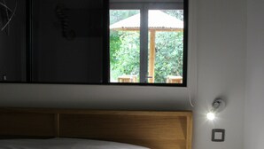 A bedroom with a bed, a window, and a bedside table. - Résidence les Caraibes (Sérignan)