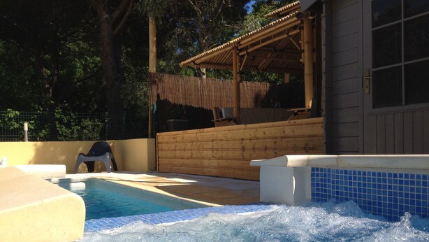 A hot tub area with a wooden deck and a covered seating area. - Résidence les Caraibes (Sérignan)