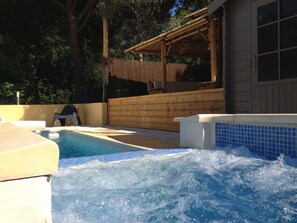 A hot tub area with a wooden deck and a covered seating area. - Résidence les Caraibes (Sérignan)