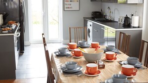 A modern kitchen with a dining area set for a meal. - Thomas Deluxe Bungalow (London)
