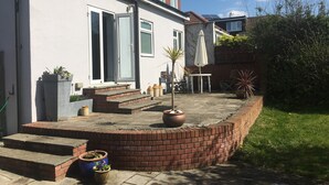 A residential property with a patio, steps leading to the entrance, a satellite dish, and a brick wall. - Thomas Deluxe Bungalow (London)