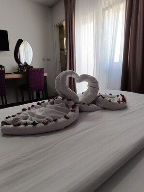 A hotel room with a bed, a desk, and a mirror.