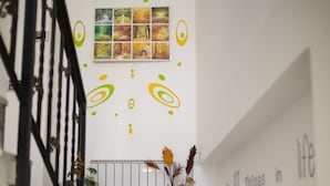 A staircase with a marble finish, a black metal railing, a potted plant, and a wall with framed pictures and decorative circles.