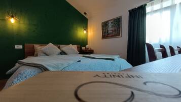 Une chambre d’hôtel avec un mur d’accent vert, un lit avec une literie à motifs, une table de chevet avec une lampe et un tableau au mur.