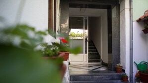 A staircase leading to an interior space, with potted plants on the steps and a door at the top.