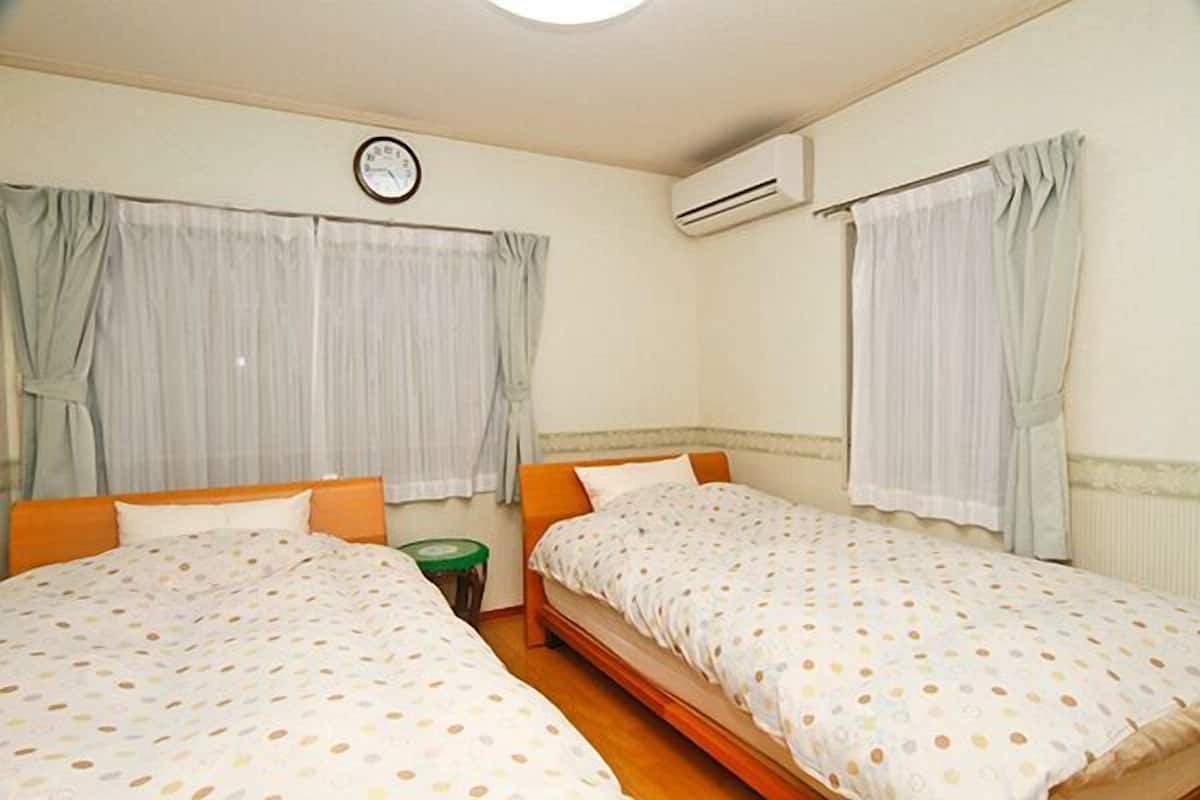 A room with two beds, a clock, an air conditioner, and curtains.