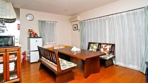 Un comedor con una mesa y sillas de madera, un microondas, un refrigerador y un extintor.