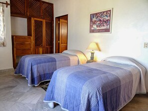A room with two beds, wooden wardrobe, and a painting on the wall.