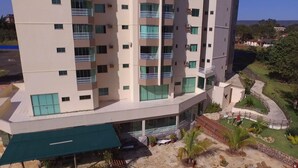 A multi-story hotel with balconies, a covered outdoor seating area, and a landscaped garden. - Thermas do Bosque Lineacaldas (Caldas Novas)