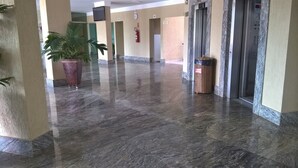 A spacious lobby with a polished marble floor, a large potted plant, and an elevator. - Thermas do Bosque Lineacaldas (Caldas Novas)