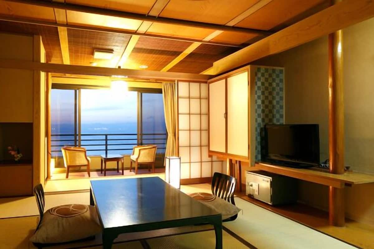 Una habitación con una mesa de comedor, sillas, un televisor y vista al mar.