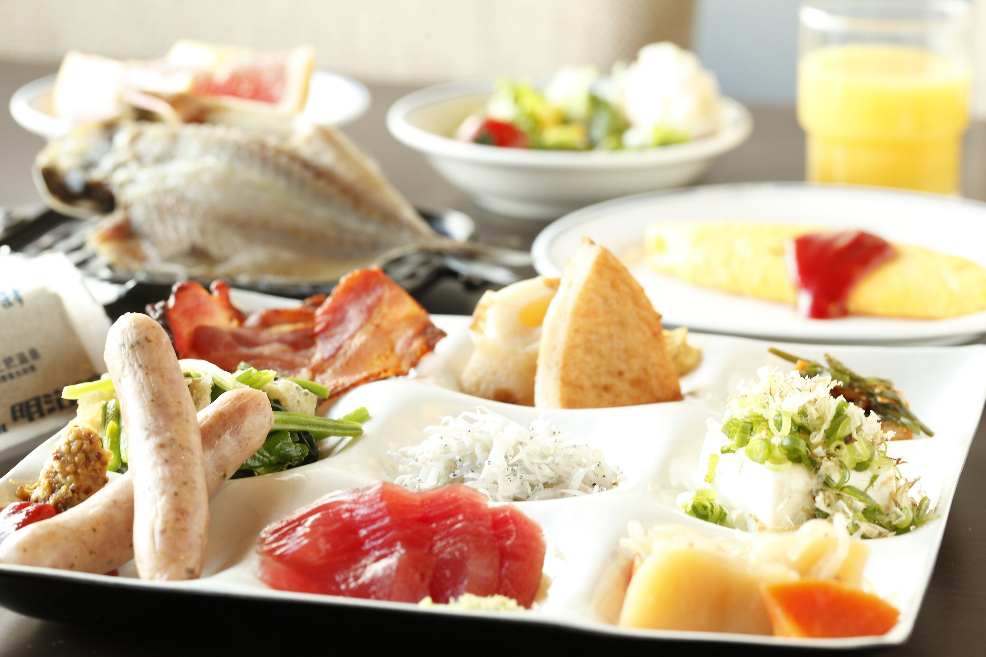 A variety of dishes including fish, bacon, and vegetables on a white plate.