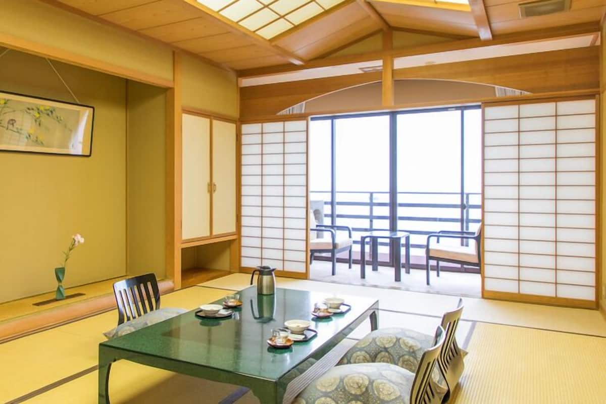 Una habitación japonesa tradicional con suelo de tatami, una mesa baja con juego de té y puertas correderas.