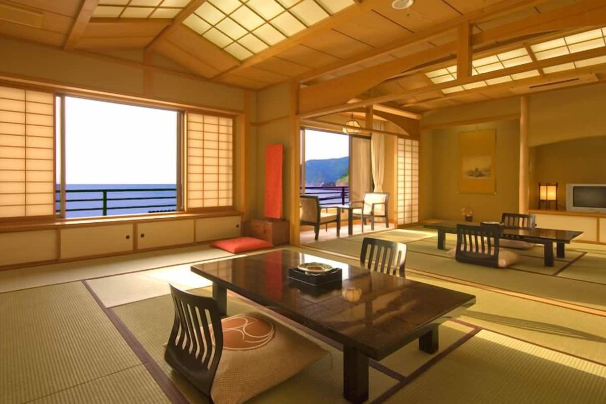 Una habitación tradicional japonesa con suelo de tatami, una mesa baja y puertas correderas.