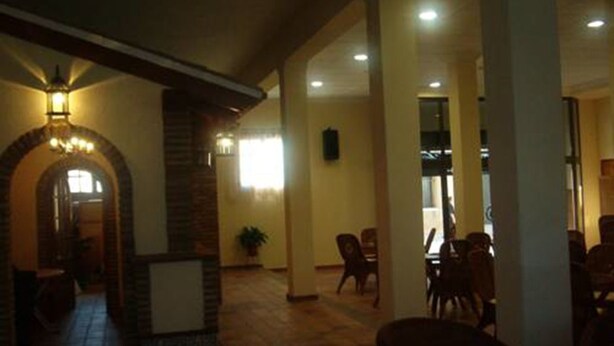 A spacious indoor area with a high ceiling, a stone fireplace, and a seating area with chairs and tables. - Hotel Luz de Guadiana (Ayamonte)